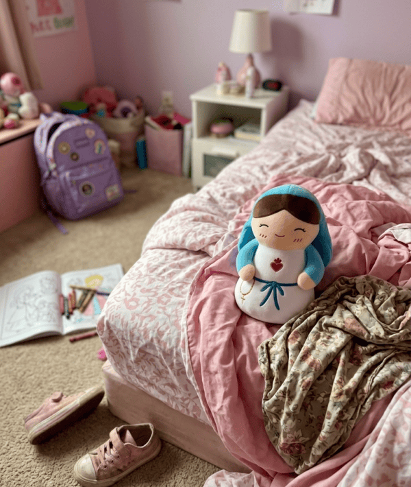Virgin Mary plushie on an unmade bed