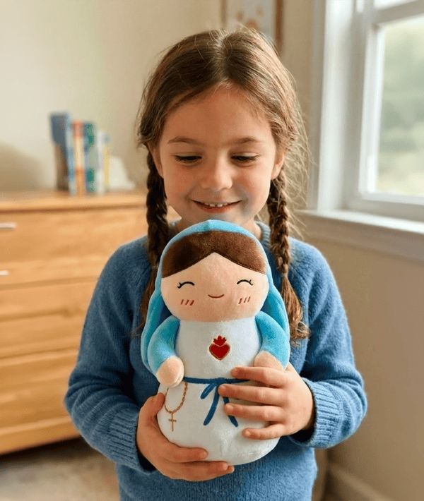 Little girl holding the virgin Mary plush toy