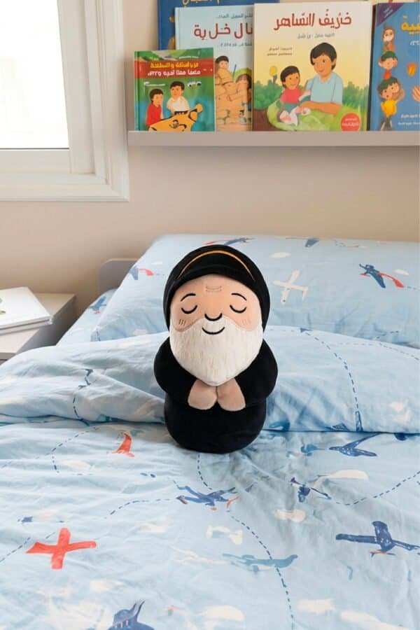 Saint Charbel plushie, a Maronite Catholic gift, on a child's bed in a cozy bedroom