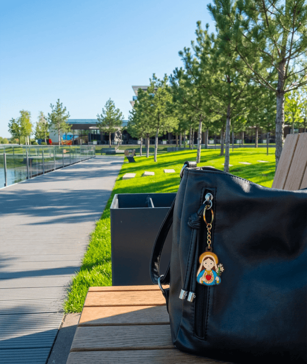 Virgin Mary keychain on a bag in a park