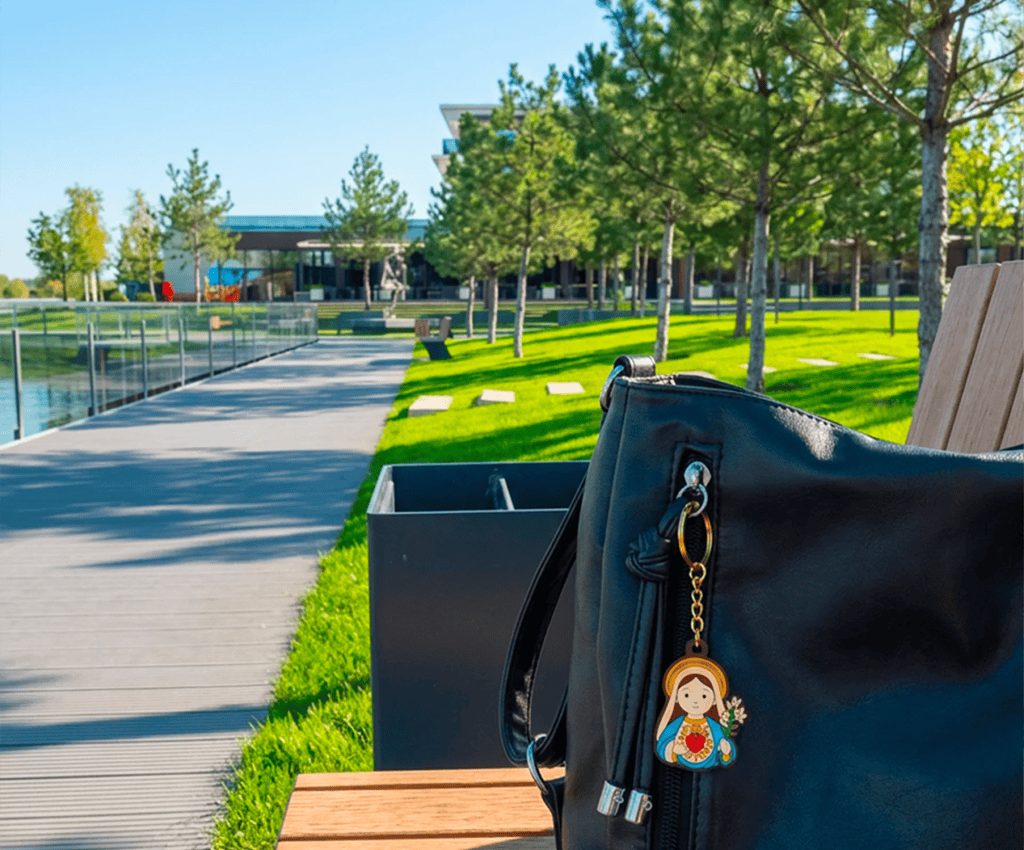 Virgin Mary keychain, a Catholic gift, attached to a purse on a park bench