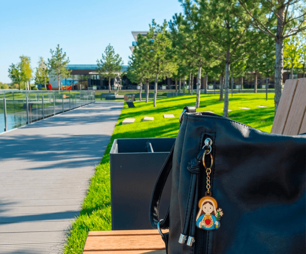 Virgin Mary keychain, a Catholic gift, attached to a purse on a park bench