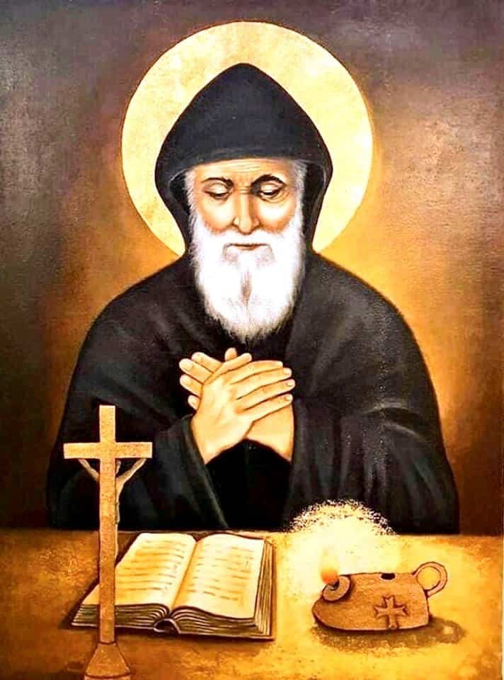 Painting of Saint Charbel praying in front of a cross with a bible