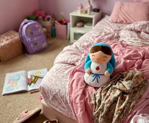 Virgin Mary plush toy on a child's unmade bed