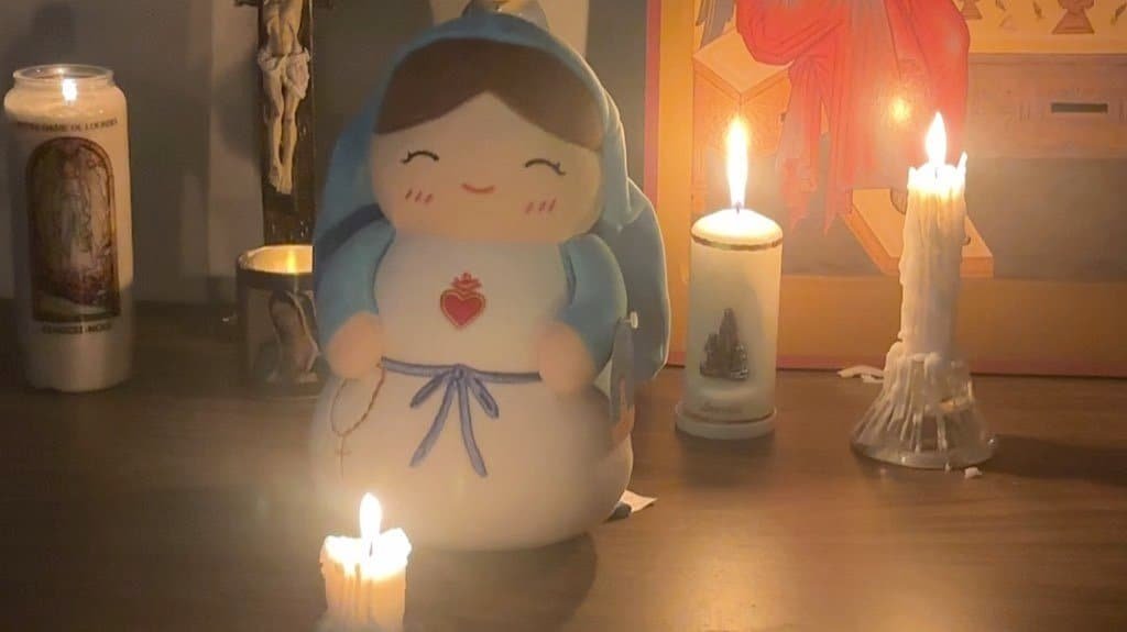 Virgin Mary plushie on a Catholic home altar lit by candles at night during Advent